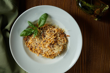 Bolognese pasta with red sauce, parmesan and minced meat. Italian spaghetti with meat in a white plate on a wooden background.