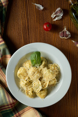 Fresh, homemade italian Ravioli with meat, decorated with parmesan and basil on a wooden background.