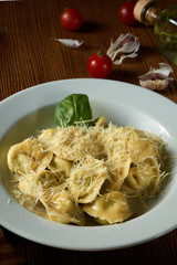 Fresh, homemade italian Ravioli with meat, decorated with parmesan and basil on a wooden background.