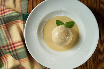 Close up White italian ice-cream into white chocolate ball with melted white chocolate in plate with mint. Italian dessert. Selective focus. Semifreddo