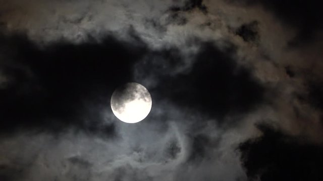 Large full moon weaving in and out of thick clouds in black sky time lapse spooky halloween