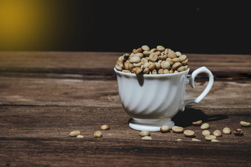 Organic Raw coffee beans in coffee cup on wood table.