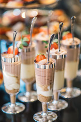 portions of mousse creamy desserts with chocolate. various snacks in three-storey services. Sweets, saltwater, cheese  balls, pickles, cheese tree, chocolate mousse, served on trays