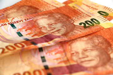 A pile, stack of orange South African two hundred rand notes with Nelson Mandela's face