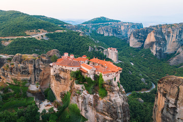 Fototapeta na wymiar Aerial view of a slide from a drone on a panorama of a mountain range. Kalampaka city, Greece. View of the cliffs of Meteora and the monasteries of Meteora. Many ancient Orthodox monasteries summer