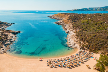 Aerial view drone sea sandy beach with sun beds and umbrellas for tourists in Greece. Turquoise...