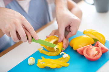 Top view of father and daughter slicing peppers and tomatoes