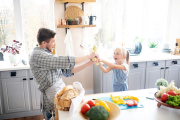 Laughing daughter having fun with father in the kitchen