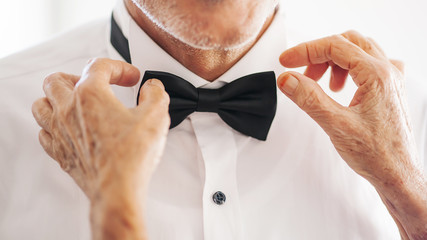 Hands of wedding groom in a white shirt dress cufflinks. Boutonnière. groom buttoning the front of...
