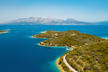 Fototapeta premium Aerial view from a drone on a panorama of the blue sea, picturesque islands and mountains in Greece, in summer on a sunny day. Beautiful coastline of the resort town. Tourism