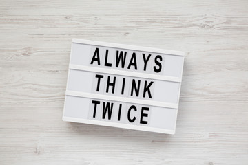 'Always think twice' words on a modern board over white wooden surface, top view. Overhead, from above. Flat lay.
