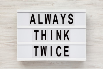 'Always think twice' words on a lightbox on a white wooden surface, top view. Overhead, from above,...