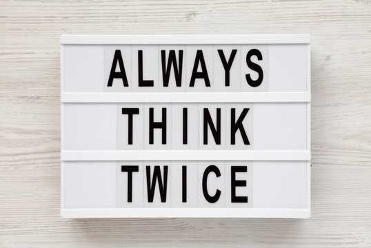 'Always think twice' words on a lightbox on a white wooden surface, top view. Overhead, from above, flat lay.