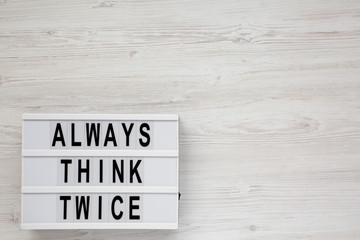 'Always think twice' words on a modern board on a white wooden surface, top view. Overhead, from above, flat lay. Copy space.