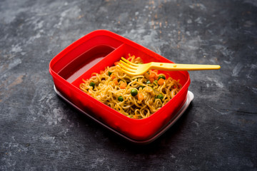 Lunch Box / Tiffin for Indian kids, contains hot noodles with fresh vegetables along with tomato ketchup. selective focus