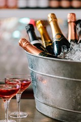 Vertical shot of a bucket filled with ice and champagne near two cocktails on the counter © Freddie Marriage/Wirestock