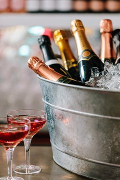 Vertical shot of a bucket filled with ice and champagne near two cocktails on the counter