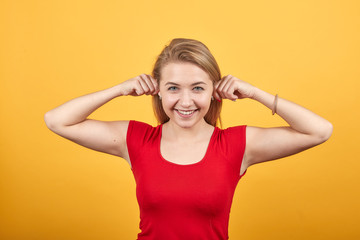 young blonde girl in red t-shirt over isolated orange background shows emotions