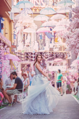 Obraz na płótnie Canvas beautiful bride in a light grey luxurious wedding dress in a street with rose flowers