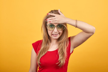 young blonde girl in red t-shirt over isolated orange background shows emotions