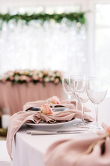 A beautiful table service at a modern wedding with burgeon of fresh flower on a beige napkin