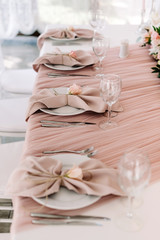 A luxurious service of the groom and bride wedding table with expensive dishes, glasses and dressed cloth napkins.