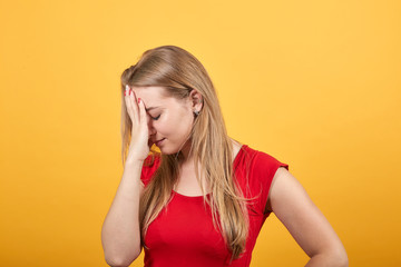 young blonde girl in red t-shirt over isolated orange background shows emotions