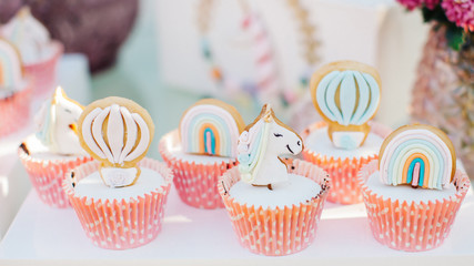 Unicorn sugar cookies decorated with royal icing and food glitter on a white background. various cookies on white serving. unicorn, cloud, flying balloon and rainbow.