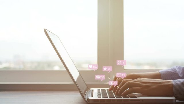 4K. people using notebook computer laptop for social media interactions with pop up of notification icons from friend in social network with like, message, email, mention and star above keyboard