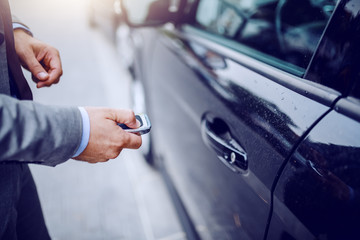 Close up of man unlocking his car on rainy weather.