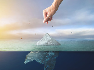 Hand throwing plastic bag floating in ocean, environment pollution