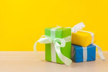 Gifts with ribbons on bright yellow background