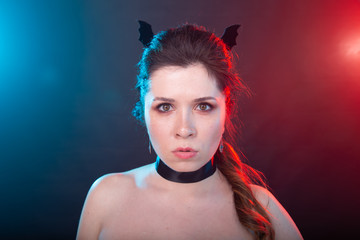 Dark fashion, halloween and people concept - gothic woman in bat ears over the dark background