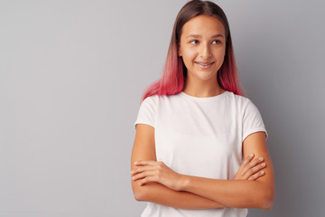 Young girl teenager with pink hair happy and smiling over gray background