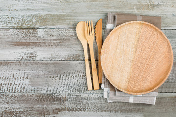 Top view of wooden plate and cutlery utensils on wooden table background. Empty plate. Mockup food concept. Copy space, place for object