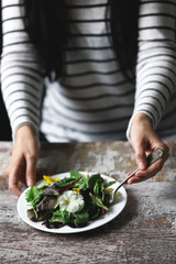 A plate of salad in the hands of a slender girl. Beautiful girl eating flowers salad. Diet concept. Healthy food concept.