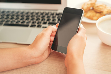 Happy woman with smartphone and computer at office