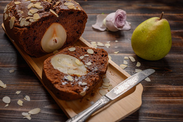 Selective focus sliced homemade chocolate pear cupcake with ginger and cardamom on a wooden tray. Near slice of with a half pears and box. The rose bud in the background