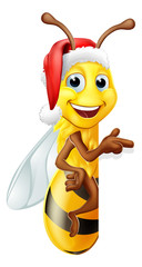 A Christmas bumble bee cartoon character in a Santa Claus hat peeking around a sign and pointing