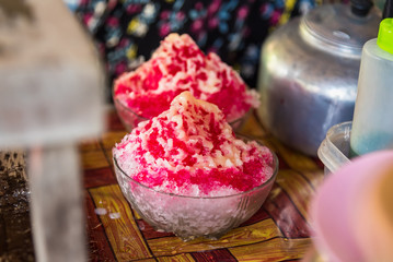 Close up the shave ice with red sugar syrup, topping with sweetened condensed milk.