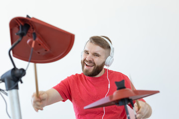 Drummer, hobbies and music concept - young man drummer in red shirt playing the electronic drums