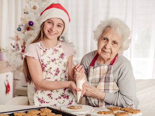 Grandmother with granddaughter decorate cookies