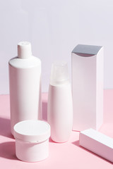 Composition of various skin care products, cosmetic products on a pink background.