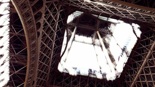 Zoom out from the inside of the historic Eiffel Tower landmark pull back shot Paris France