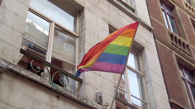 Still shot of gay pride banner flag rainbow blowing in wind mounted to building