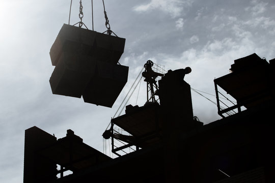 Construction site. Workers  and crane silhouette during development of the biulding