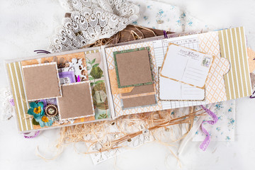 Scrapbooking handmade photo album. Diy. Top view on table with elements for scrapbooking, cut paper, die cuts, paper flowers, ribbons,embossing. Pastel colors. Women's hobby