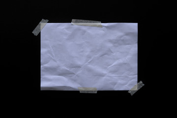 Empty old wrinkled white A4 paper stick by adhesive tape at the outdoor flat black coloring cement...
