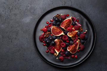 Fig, grape, raspberry and pomegranate salad on black plate
