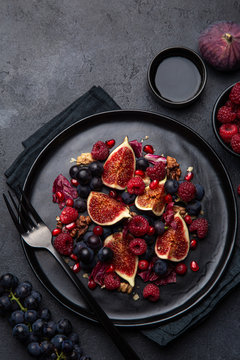 Fruit fig, grape, raspberry and pomegranate salad on black plate